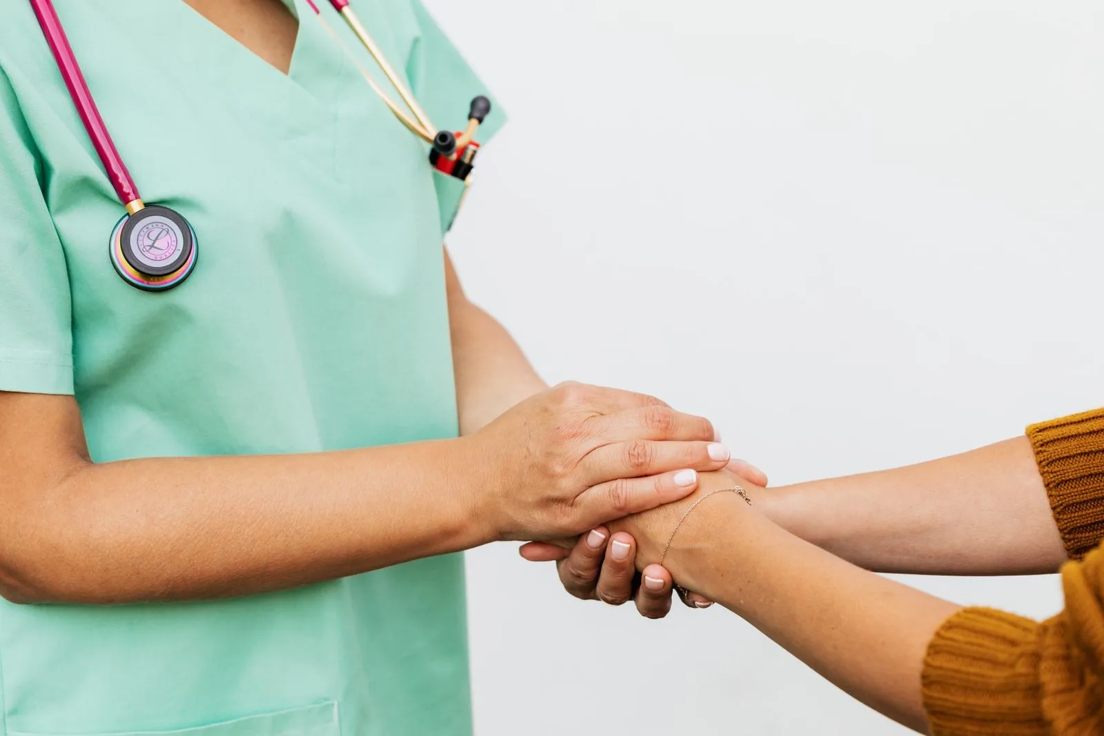 A clinician holding a patient's hands during a care conversation.