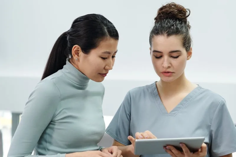 Two clinicians reviewing a patient's treatment-response data together on a tablet during a consultation.