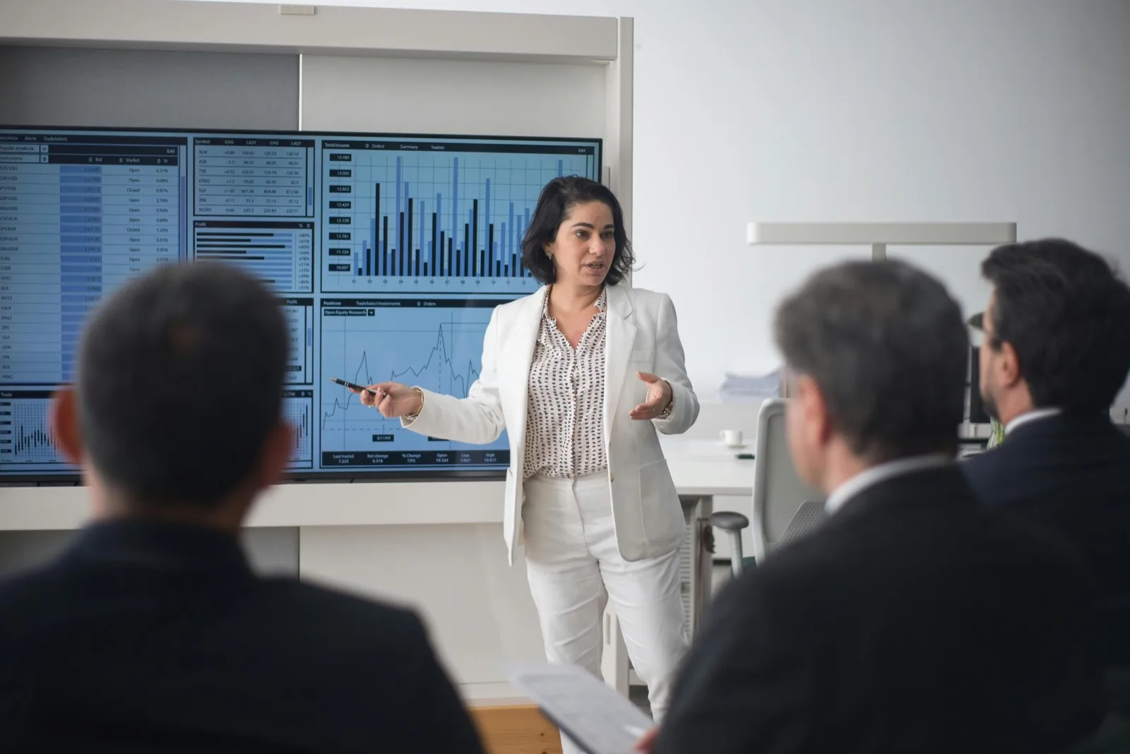 A focused analyst with braided hair and glasses reviews data charts and analytics on a laptop at a clean white desk, evoking a payer reviewing claims and outcome data.