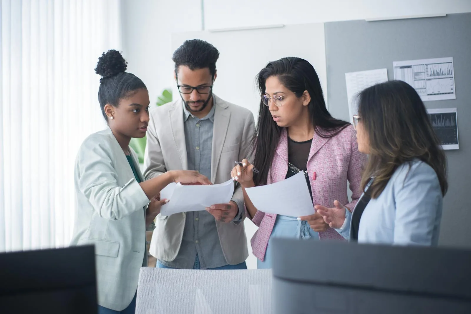 A diverse, multidisciplinary team of healthcare and technology professionals collaborating over documents and data in a bright, modern office